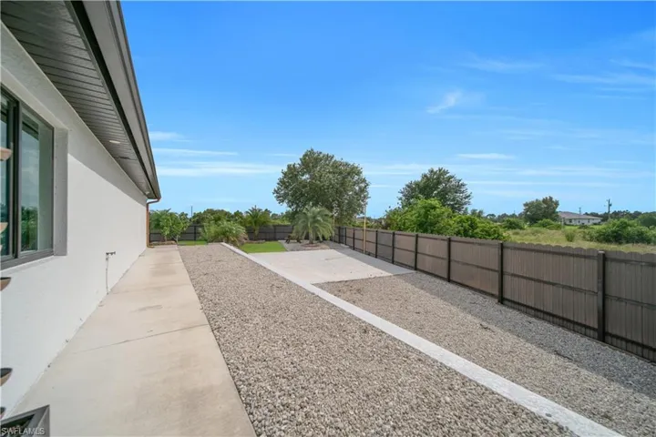 Expansive outdoor space featuring a concrete patio, gravel landscaping, and a privacy fence
