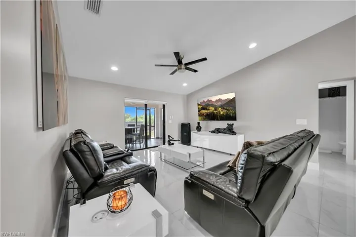 Spacious living area featuring vaulted ceilings, recessed lighting, and large format tile flooring