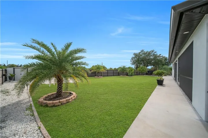 Expansive green lawn featuring a mature palm tree with brick landscaping