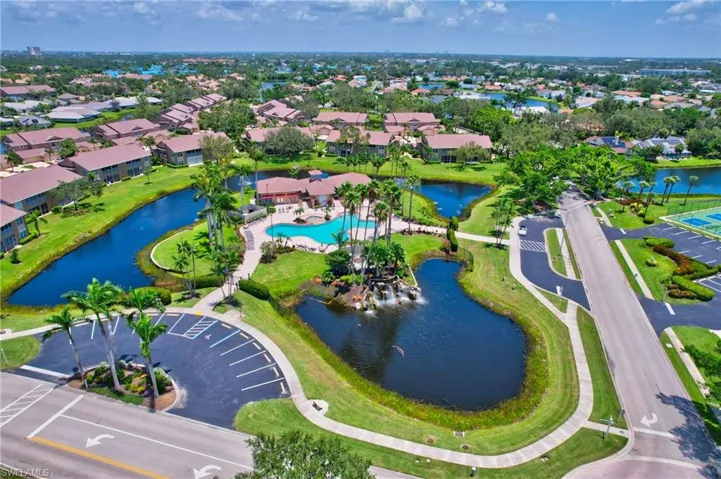 Aerial view of residential area featuring a nearby body of water and a pool area