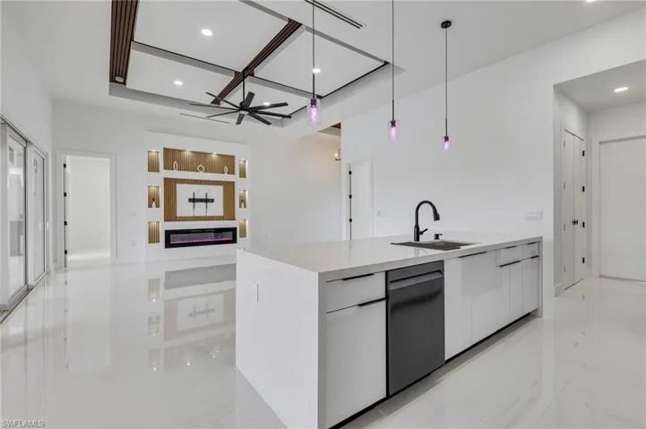 Kitchen featuring white cabinets, modern cabinets, decorative light fixtures, light stone countertops, and dishwashing machine
