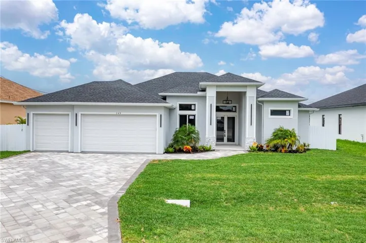 Prairie-style home featuring decorative driveway, an attached garage, and stucco siding
