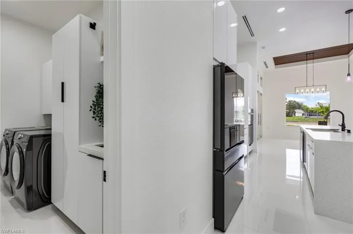 Kitchen with white cabinets, modern cabinets, hanging light fixtures, light tile patterned floors, and light stone countertops