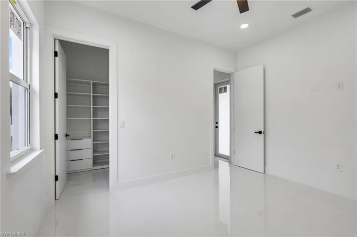 Unfurnished bedroom with a walk in closet, light tile patterned flooring, ceiling fan, and recessed lighting