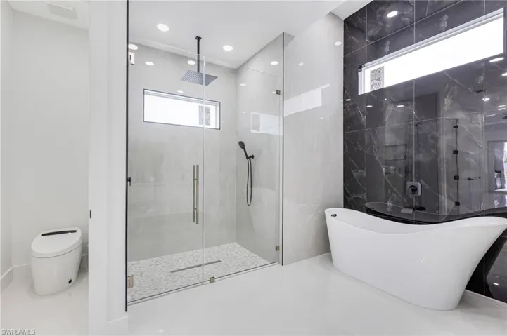 Full bath with a marble finish shower, a freestanding tub, tile patterned floors, and tile walls