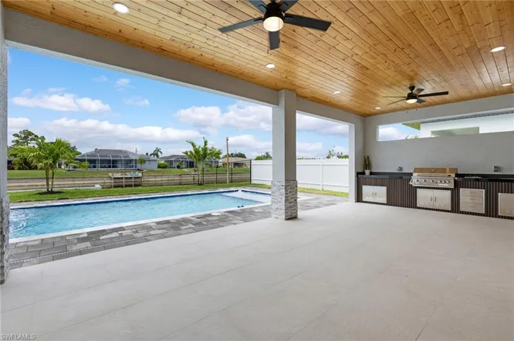 Outdoor pool with an outdoor kitchen, a fenced backyard, a patio, and a ceiling fan