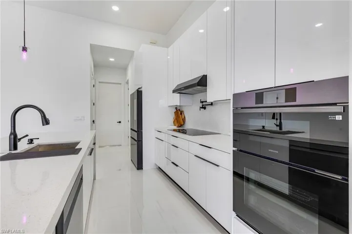 Kitchen featuring modern cabinets, white cabinetry, hanging light fixtures, light stone counters, and black appliances