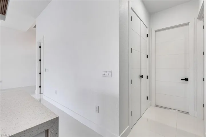 Corridor with light tile patterned flooring and baseboards