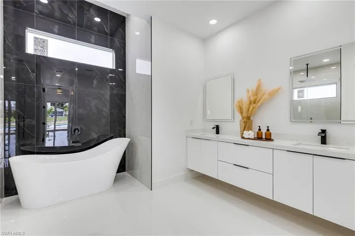 Full bathroom featuring a freestanding tub, double vanity, walk in shower, and recessed lighting