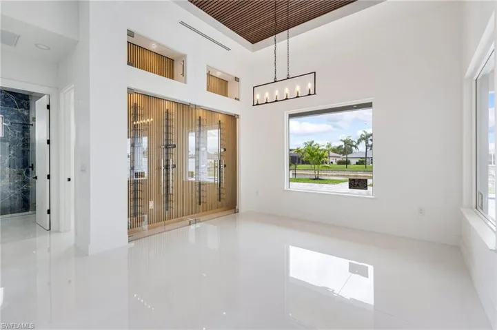 Tiled empty room with healthy amount of natural light and a towering ceiling