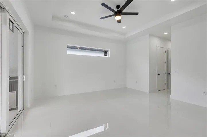 Spare room featuring a tray ceiling, light tile patterned floors, recessed lighting, and a ceiling fan