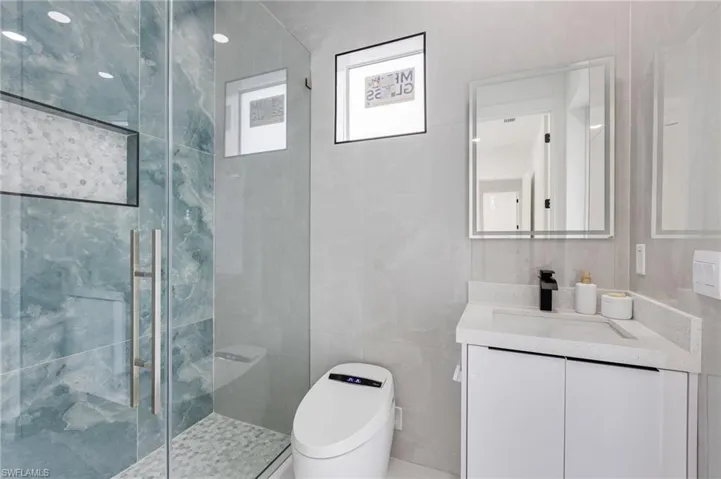 Full bath with vanity, tile walls, and a stall shower