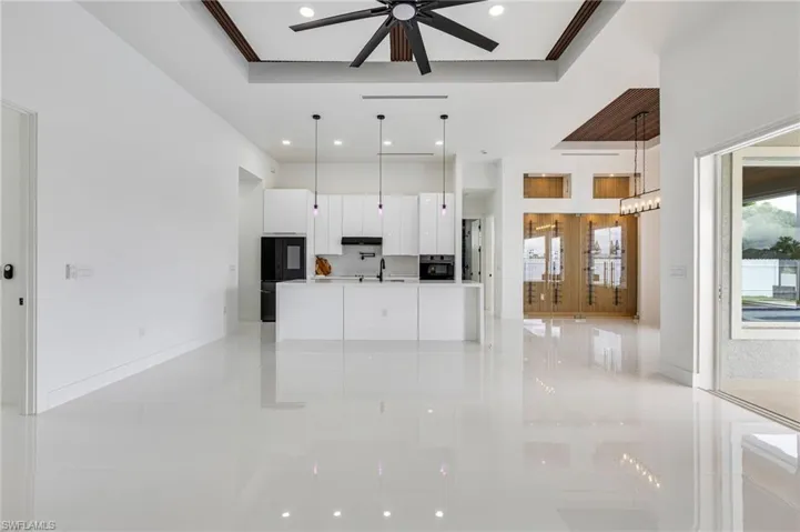 Unfurnished living room with a raised ceiling, a ceiling fan, light tile patterned floors, recessed lighting, and ornamental molding