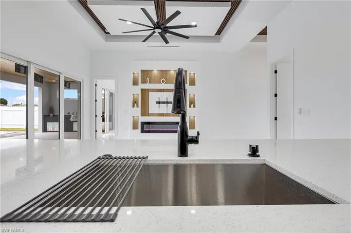Detailed view of light stone countertops, a raised ceiling, and a glass covered fireplace