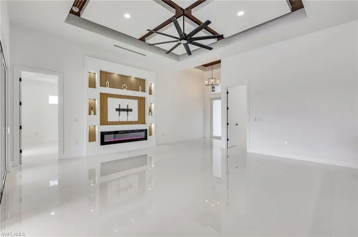 Empty room featuring tile patterned floors, a glass covered fireplace, ceiling fan, a chandelier, and recessed lighting