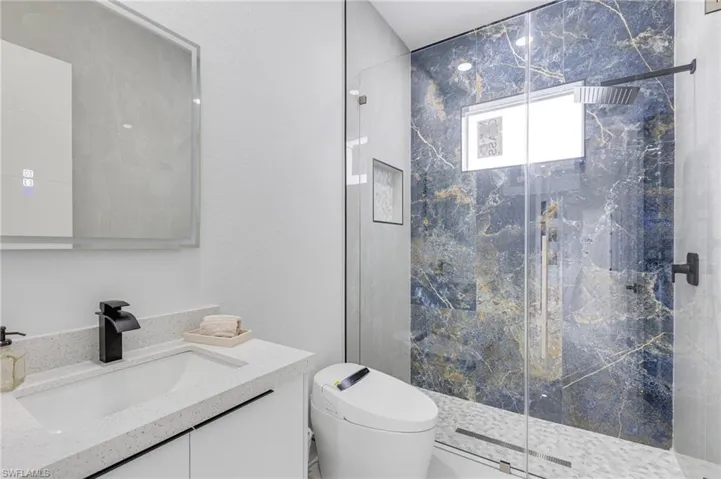 Full bath featuring a marble finish shower and vanity