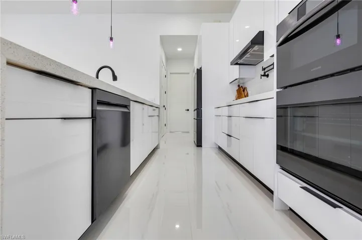 Kitchen with modern cabinets, white cabinets, wall chimney range hood, light countertops, and recessed lighting