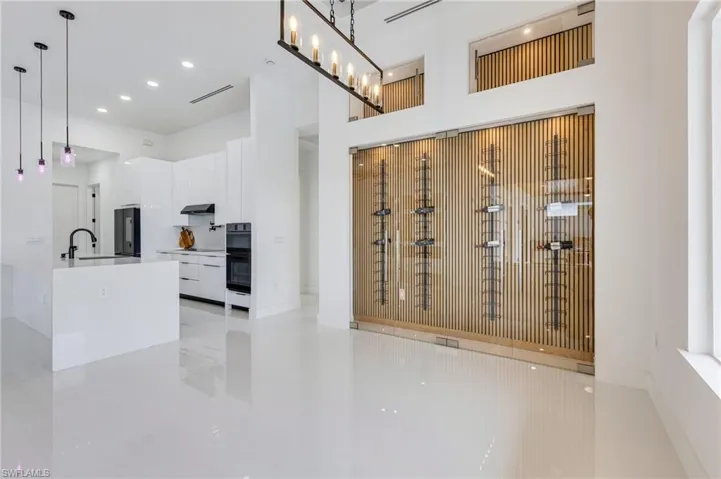 Kitchen with white cabinetry, decorative light fixtures, a high ceiling, modern cabinets, and light stone countertops