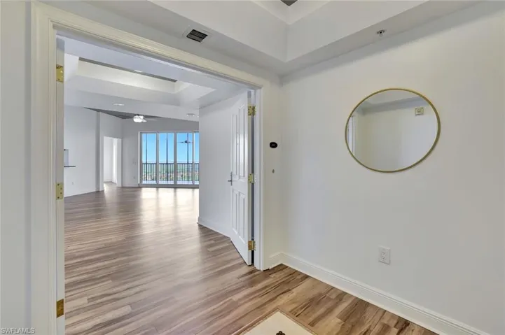 Corridor featuring light wood-style floors and a tray ceiling
