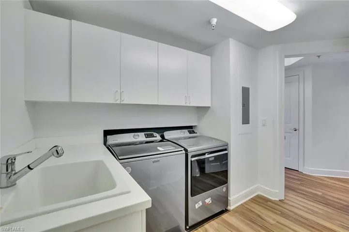 Laundry area featuring light wood-style flooring, washer and clothes dryer, and cabinet space