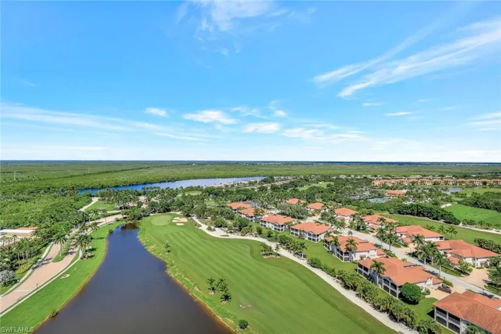 Aerial perspective of suburban area featuring a golf club and a nearby body of water