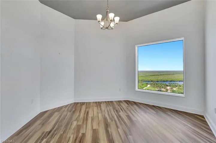 Spare room featuring light wood-type flooring, a chandelier, and a water view