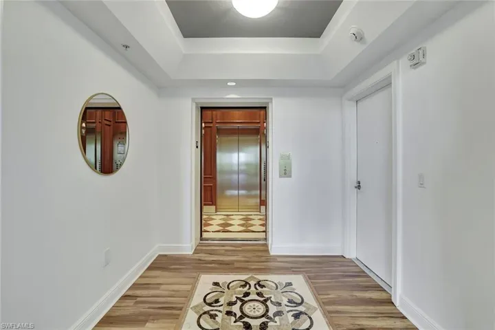 Hall with a raised ceiling and light wood-type flooring