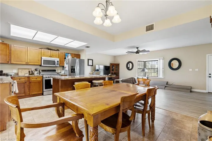 Dining space with light hardwood / wood-style flooring and ceiling fan with notable chandelier