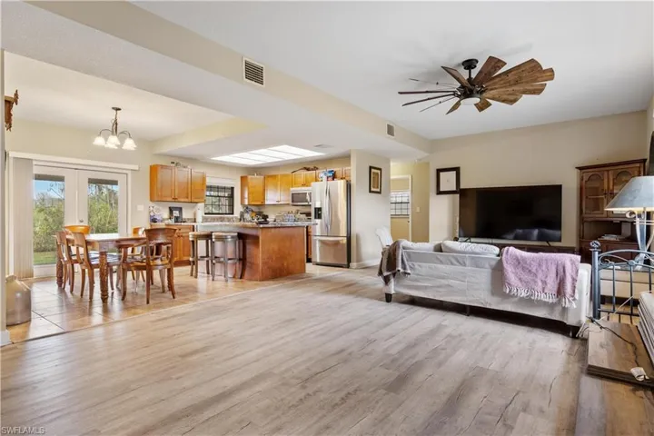 Living room featuring ceiling fan with notable chandelier and light hardwood / wood-style flooring