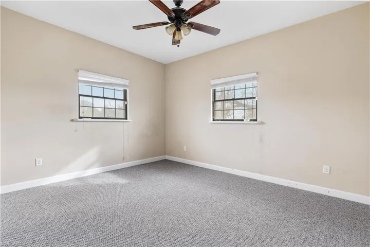 Carpeted spare room with ceiling fan and a healthy amount of sunlight