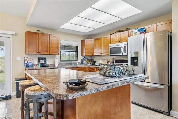 Kitchen with a breakfast bar, light tile patterned floors, a center island, and stainless steel appliances
