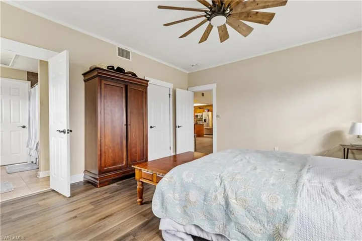 Bedroom featuring light hardwood / wood-style floors, ceiling fan, ornamental molding, and ensuite bathroom