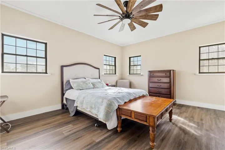 Bedroom with multiple windows, hardwood / wood-style flooring, ceiling fan, and ornamental molding
