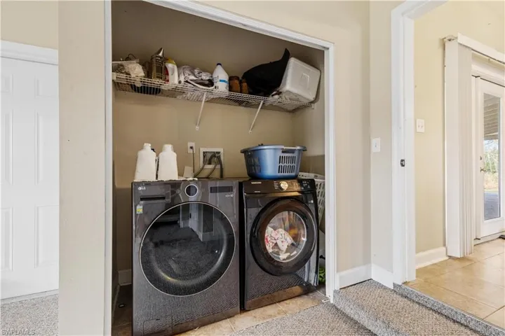 Laundry room featuring washing machine and dryer and light tile patterned flooring