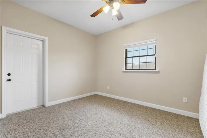 Carpeted spare room featuring ceiling fan