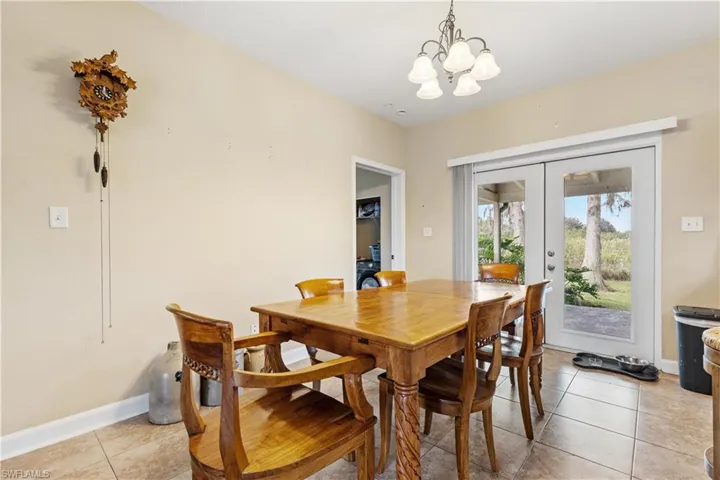 Dining space with light tile patterned flooring and an inviting chandelier
