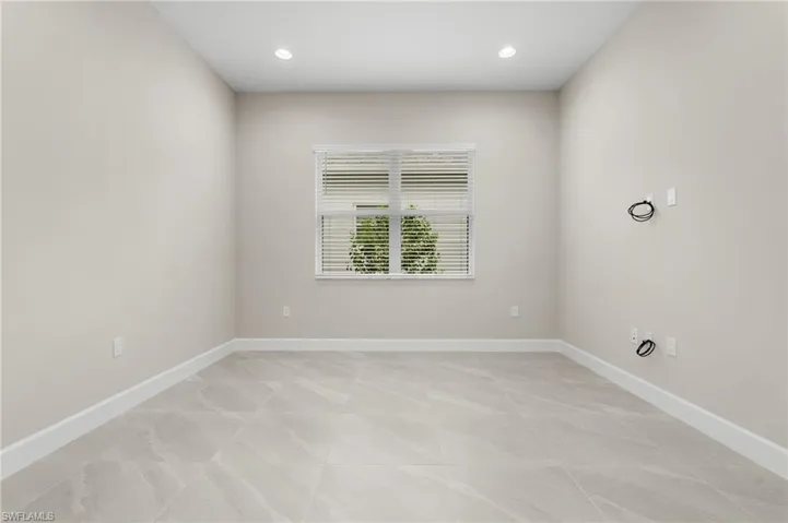 Spacious room featuring light-toned walls, contemporary recessed lighting, and large format tile flooring