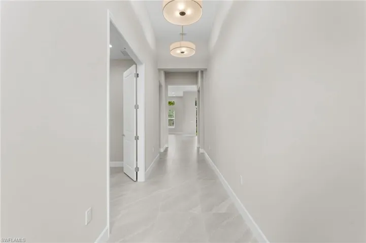 Long foyer hallway featuring light-toned walls, 24" x 24" procelain tile flooring with subtle veining, and contemporary flush mount lighting fixtures