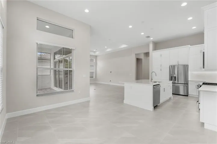Open-concept living space featuring high ceilings with recessed lighting, large format tile flooring, and a contemporary kitchen