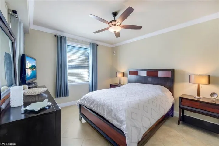 Bedroom with ornamental molding, a ceiling fan, and light tile patterned floors