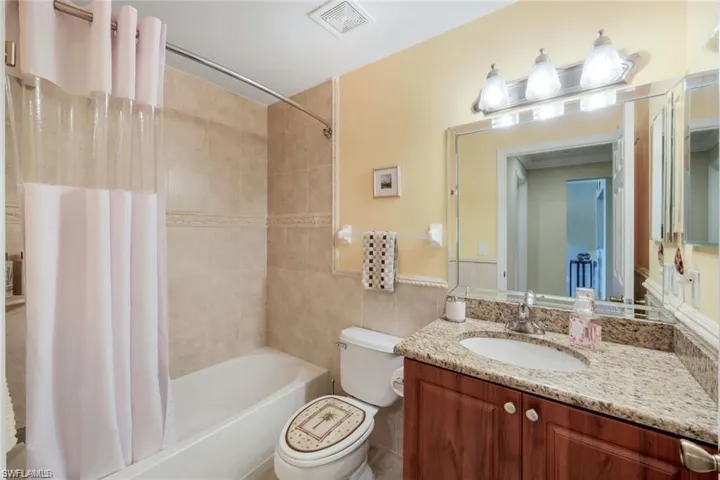 Full bathroom with shower / bath combination with curtain, vanity, and tile walls