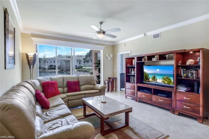 Living room featuring ornamental molding, light tile patterned floors, and ceiling fan