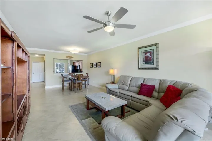 Living area featuring ornamental molding, ceiling fan, and light tile patterned floors