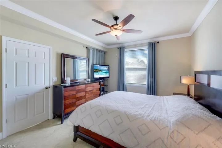 Bedroom featuring ornamental molding, light carpet, and ceiling fan