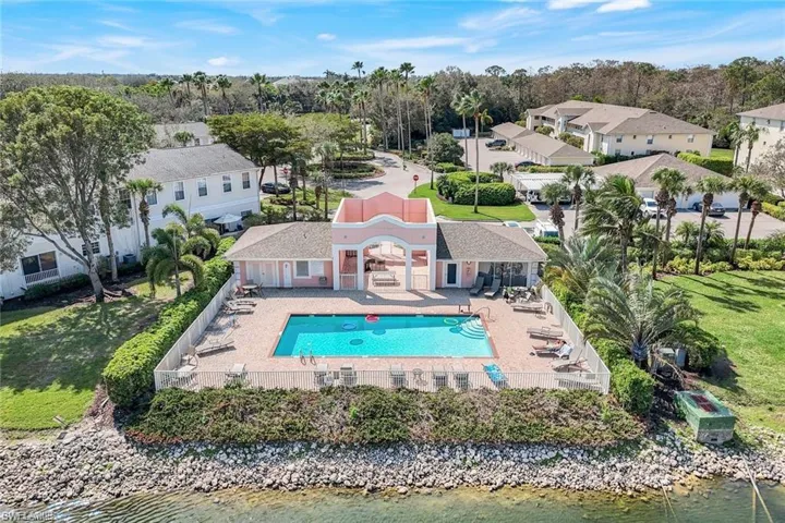 Aerial perspective of suburban area featuring a pool and a nearby body of water