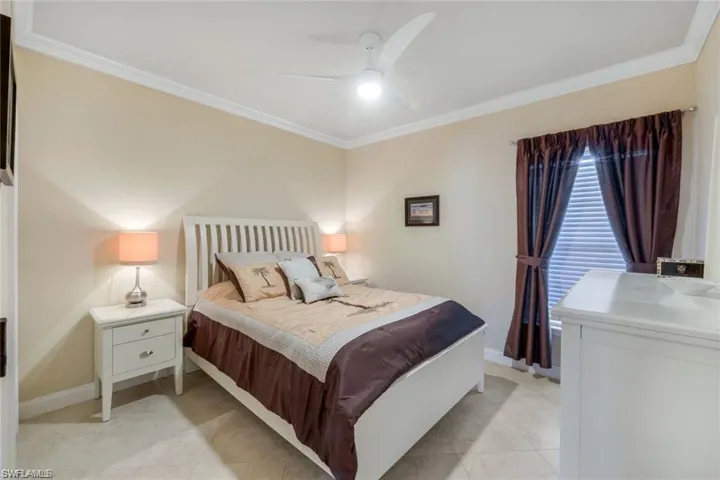 Bedroom with crown molding, ceiling fan, and light tile patterned floors
