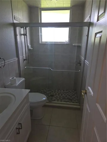 Full bathroom featuring vanity, tile patterned flooring, a stall shower, and a textured wall