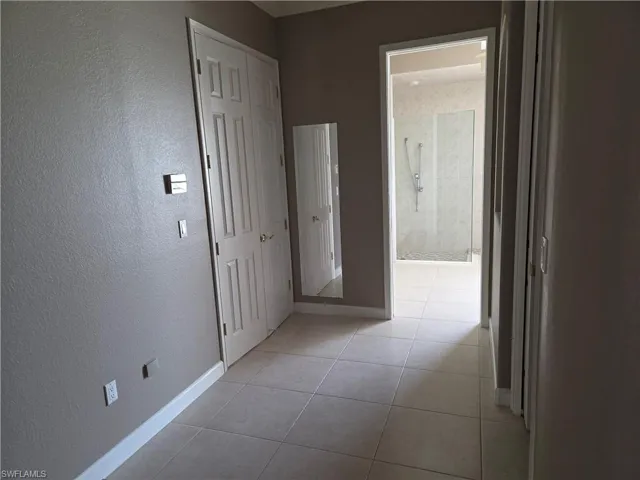 Hall with a textured wall and light tile patterned floors