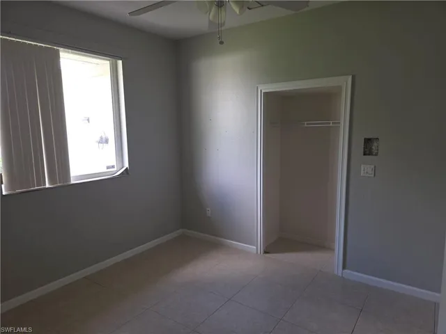 Unfurnished bedroom with a closet, tile patterned floors, and a ceiling fan
