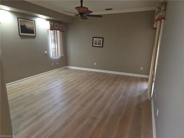 Spare room featuring wood finished floors, ceiling fan, and ornamental molding